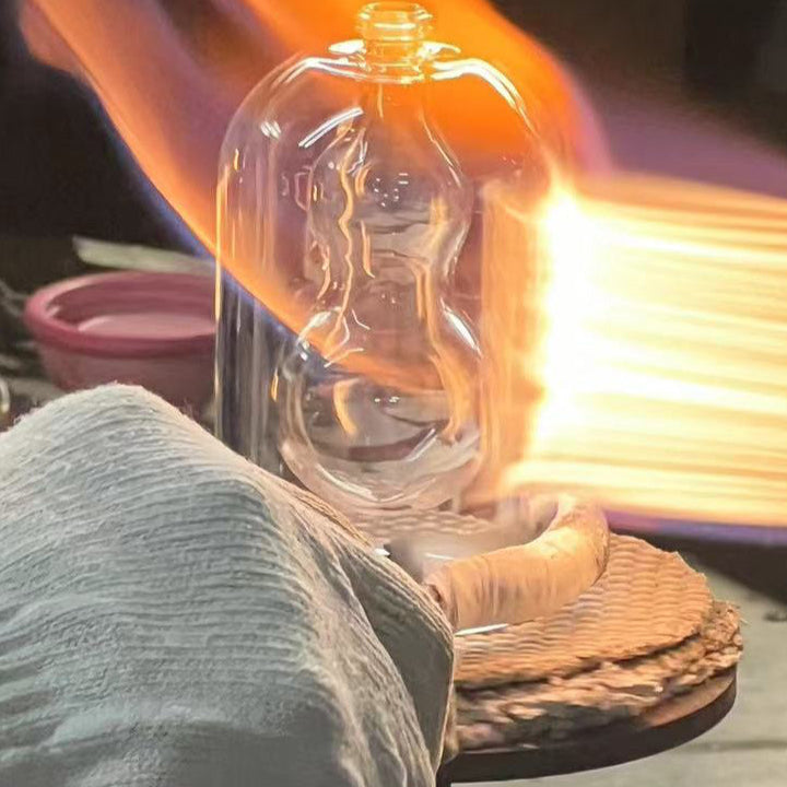 Artisan glassblower shaping a Premiere Peau bottle